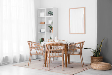 Interior of dining room with table, wicker chairs and shelving unit near white wall