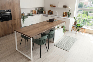 Interior of dining room with table,  counters and houseplants near white wall