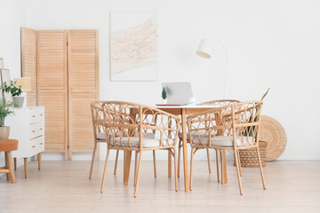 Table and wicker chairs near white wall in dining room