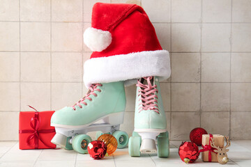 Composition with roller skates, Santa hat and Christmas decorations on light tile background