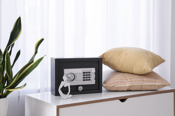 Modern safe with pillows on commode in living room