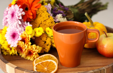 Mug of tasty green tea, flowers and apple on table in room, closeup