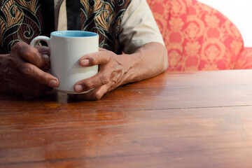 two hand of senior elder on table, loneliness old man in living room with his coffee glass with window view