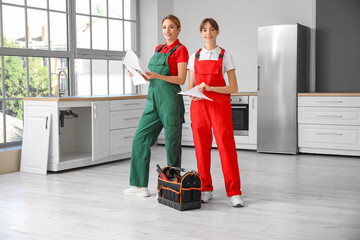 Female workers with furniture assembling instructions in kitchen