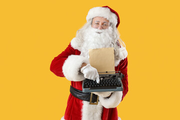 Santa Claus with vintage typewriter on yellow background