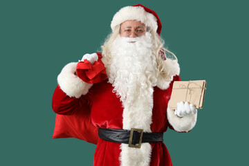 Santa Claus with letters and bag of gifts on green background