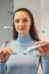 Woman squeezing toothpaste onto her toothbrush. Mouth cavity health is important to ensure healthy teeth. Daily routine.