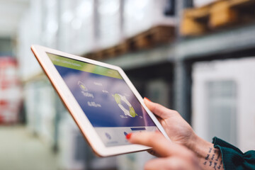 The young female owner and the man in the warehouse check the temperature, energy consumption and lights on a tablet.