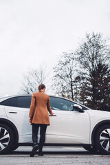 Businesswoman waiting on the sidewalk to be picked up by an electric car driver