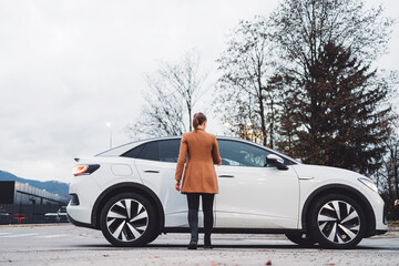 Businesswoman waiting on the sidewalk to be picked up by an electric car driver