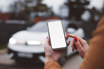 Woman charging electric car and making time adjustment on a smartphone