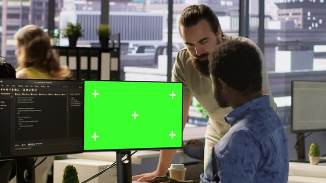 System administrator does software debugging on isolated screen PC, asking for help from coworker. Zoom in on admin fixing coding mistakes on chroma key computer, being assisted by colleague, camera A