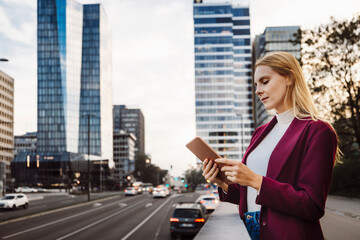 Young caucasian woman portrait on the street in dusk with digital tablet. Walking in business district.