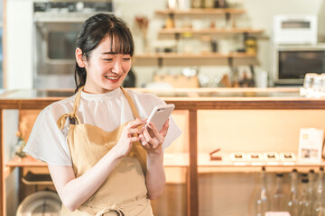 Fototapeta premium カフェ・レストラン・飲食店で働くウェイトレス・ホールスタッフをする女性（スマホ・モバイルオーダー） 