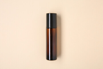 Essential oils in bottle on beige background, top view