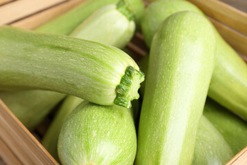 Fresh ripe zucchinis in wooden crate, closeup