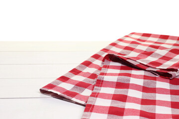 Obraz premium Folded tablecloth with checkered pattern on wooden table against white background