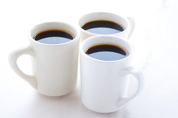 淹れたてで香りのよいコーヒーが入った3つのマグカップで、3人がコーヒーブレイクを楽しんでいるイメージ
