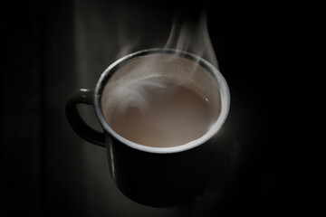 The smoke rising from a cup of hot coffee in the morning