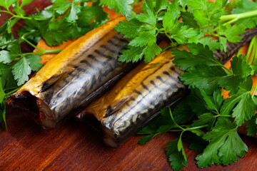 Smoked mackerel cut into pieces with parsley on a table