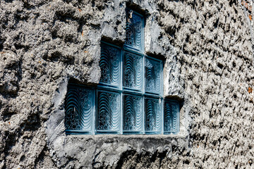 Textured wall with a geometric arrangement of decorative glass blocks, creating a unique pattern that blends rustic and modern design elements, perfect for architectural use