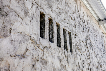 Close-up of a textured stone wall with vertical slits, creating a unique architectural detail that combines rustic and minimalist elements, perfect for backgrounds or design use
