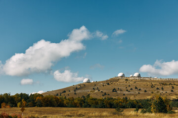 Scenic Landscape with Three White Domes on Hilltop Surrounded by Trees in Grassy Field