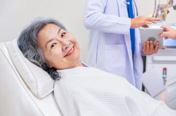 portrait active senior woman happy,smiling,looking at camera while having lifting, botox, rejuvenation or skin care in aesthetic clinic,background blurred a doctor team