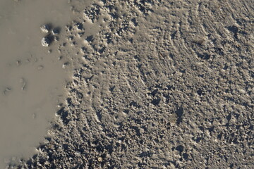 after the rain, puddle of water, rain puddle on dirt road or bad road with holes as road damage, muddy and wet, water in the depression, close-up bird's eye view from above