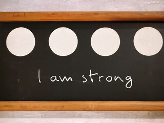Chalkboard with handwritten text I Am Strong, self reminder that you are capable of anything -...