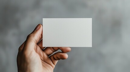 Fototapeta premium A Hand Holding a Blank White Card with a Textured Surface