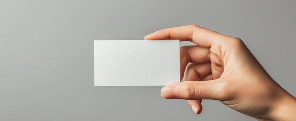 Obraz premium A Hand Holding a Blank White Card Against a Gray Background
