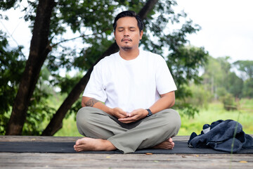 Fototapeta premium A man is sitting on a wooden platform with his legs crossed