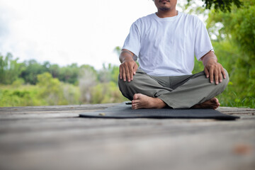 A man is sitting on a mat on a wooden bridge