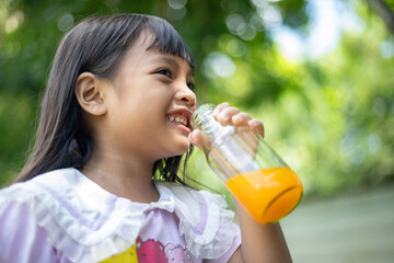 A young girl is drinking a glass of orange juice