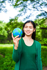 An Asian woman holds a globe in a green forest,symbolizing the importance of preserving nature.emphasizes balance between humans, natural resources,sustainable environmental development  protect