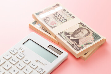 ピンク背景に一万円の札束と電卓
