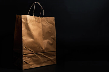 Brown kraft paper bag with visible texture on a black background, lit from the left.