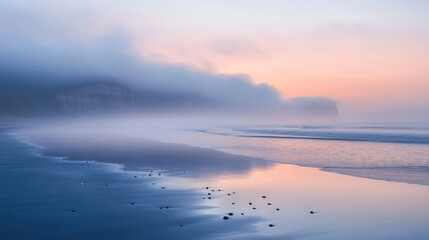 Fototapeta premium A serene beach scene at dawn, shrouded in mist with gentle waves lapping at the shore.