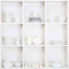 Shelves in wooden rack with white kitchen dishes close up