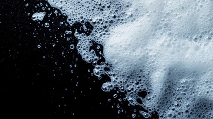 Obraz premium A close-up view of white soap bubbles against a dark background, creating a unique and abstract texture perfect for backgrounds.