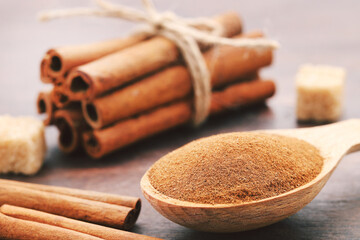 Cinnamon powder with sticks on brown wooden background
