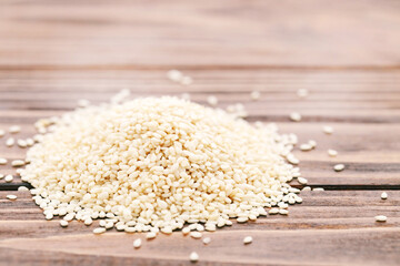 Heap of sesame seeds on brown wooden background