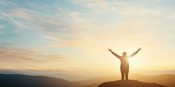Person standing on mountain peak with arms raised at sunrise, embracing the beauty of nature and freedom.