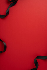 A striking red vertical background is adorned with elegantly flowing black ribbons, perfect for...