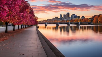 Fototapeta premium A Tranquil Cityscape With A Bridge Spanning Over A Calm River In Front Of A Colorful Autumnal Skyline
