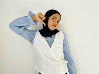 Young Asian woman showing thumbs down gesture with blue shirt and white outer on white background