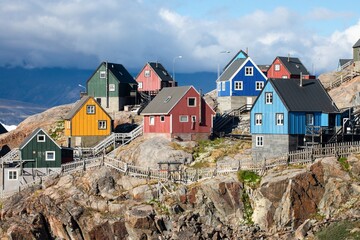 Baffin Bay, the colorful typical houses in the small village of Uummannaq, the Greenland. Icefjord in Greenland and the silhouette of the high mountain ridge in the background under the blue melting g