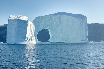 A massive iceberg with arch. Melting of a glacier by the coast of Greenland. Amazing iceberg on the sea, we can still see this before complete climate change. Icefjord Global warming.