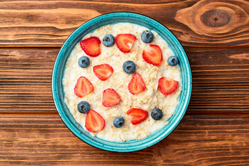 Homemade breakfast . Oatmeal with milk and berries . Top view